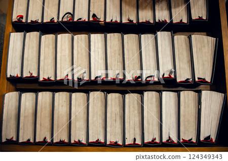 A row of hymn books with red bookmarks on a wooden shelf inside a church. A symbolic representation 124349343