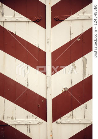 Vintage wooden shutters with diagonal red and white stripes. Close-up of weathered wooden shutters 124349360