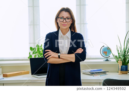 Portrait of serious confident business mature woman with crossed arms in home office 124349502