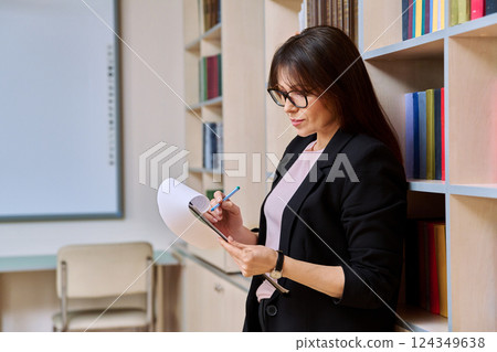 Portrait serious middle aged woman with clipboard inside library office 124349638