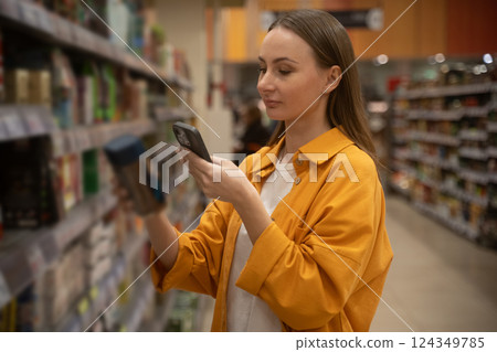 Woman scans coffee can in grocery store during shopping trip in the afternoon Woman scans coffee can in grocery store during shopping trip in the afternoon 124349785