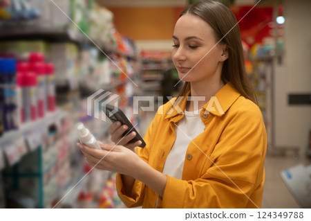 Scanning household chemicals in a grocery store aisle for safe product choices Scanning household chemicals in a grocery store aisle for safe product choices 124349788