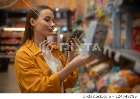 Woman scans cornflakes in grocery store while shopping for breakfast options during weekday Woman scans cornflakes in grocery store while shopping for breakfast options during weekday 124349789