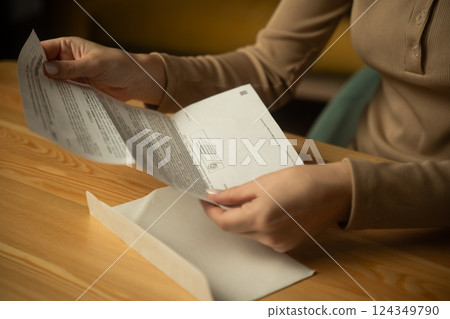 Woman eagerly opens envelope containing important letter at home 124349790