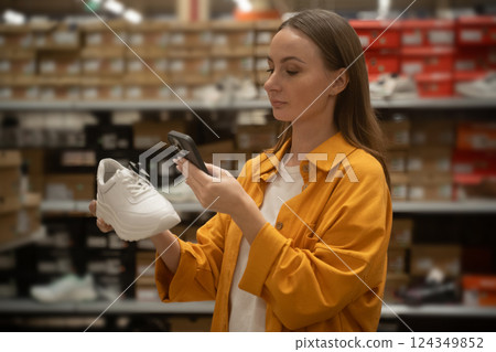 Woman uses smartphone to scan shoes in retail store for price and details 124349852