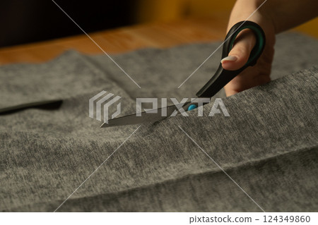 Cutting fabric to create a unique garment in a home crafting workspace 124349860