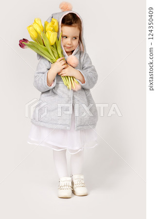 Thoughtful Toddler in Bunny Costume Holding a Bouquet of Yellow and Burgundy Tulips 124350409
