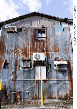 An outdoor unit of an air conditioner installed in an old, dilapidated building An outdoor unit of an air conditioner installed in an old, dilapidated building 124350543
