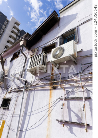 An outdoor unit of an air conditioner installed in an old, dilapidated building 124350548