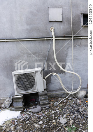 An outdoor unit of an air conditioner installed in an old, dilapidated building 124350549