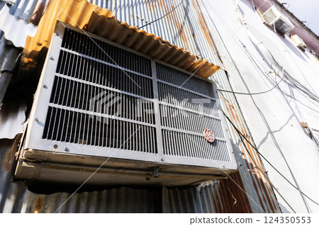An outdoor unit of an air conditioner installed in an old, dilapidated building 124350553