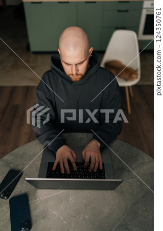 Vertical top view of serious male programmer in casual clothes typing code on laptop, developing software in dark home office, focused looking to screen. Freelancer remote working from home. 124350761