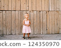 Little girl stands against the background of a wooden wall. High quality photo 124350970