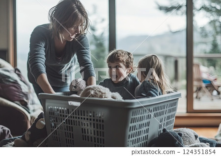 A woman and two children sit in a laundry basket of stuffed animals 124351854