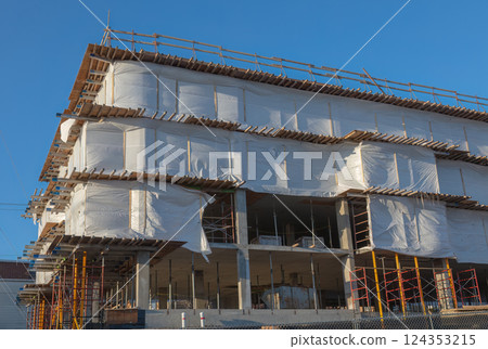 Modern Building Under Construction Wrapped in Protective Sheets Modern Building Under Construction Wrapped in Protective Sheets 124353215