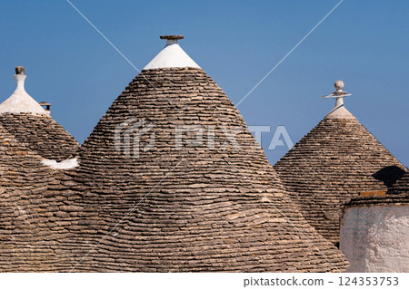 Three small buildings with pointed roofs, traditional Trulli houses in Alberobello Three small buildings with pointed roofs, traditional Trulli houses in Alberobello 124353753