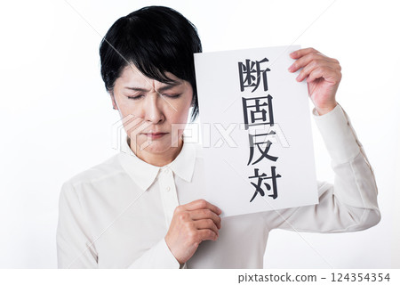 A middle-aged woman with deep wrinkles on her brow and a frown as she holds up a piece of paper that says "firmly opposed" A middle-aged woman with deep wrinkles on her brow and a frown as she holds up a piece of paper that says "firmly opposed" 124354354
