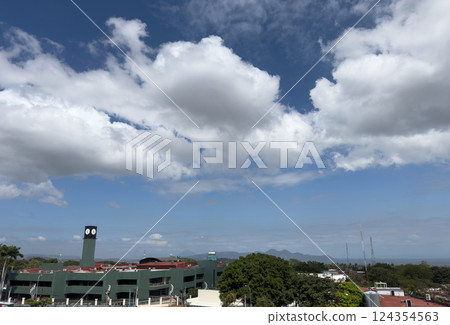 Clouds drift over a vibrant cityscape with distant mountains in daytime sky 124354563