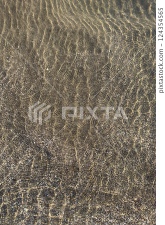 Clear water ripples over sandy beach during bright sunny day 124354565