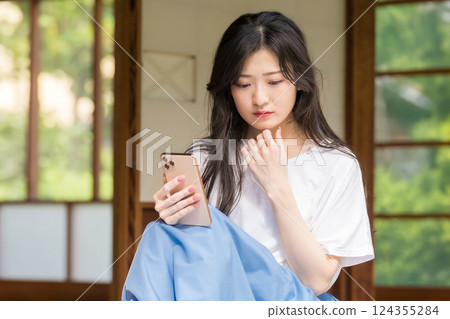 A young woman thinking with a smartphone in her hand 124355284