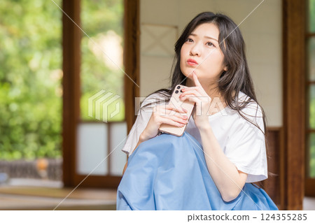 A young woman thinking with a smartphone in her hand 124355285