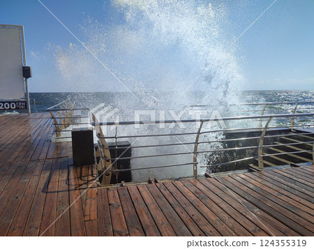Large wave hitting wooden pier jetty with a lot of splashes on a sunny day. Storm, stormy sea. Weather. Travel, tourism,vacation. Coast, coastal, shore Large wave hitting wooden pier jetty with a lot of splashes on a sunny day. Storm, stormy sea. Weather. Travel, tourism,vacation. Coast, coastal, shore 124355319
