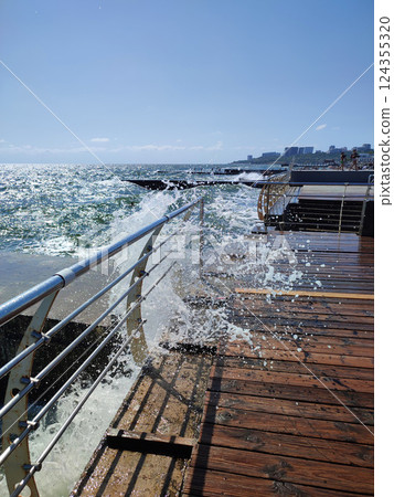 Large wave hitting wooden pier jetty with a lot of splashes on a sunny day. Storm, stormy sea. Weather. Travel, tourism,vacation. Coast, coastal, shore Large wave hitting wooden pier jetty with a lot of splashes on a sunny day. Storm, stormy sea. Weather. Travel, tourism,vacation. Coast, coastal, shore 124355320