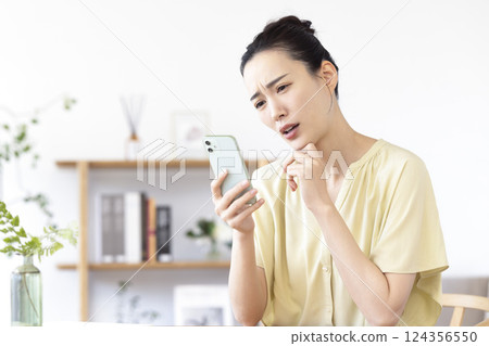 woman looking at smartphone in living room woman looking at smartphone in living room 124356550