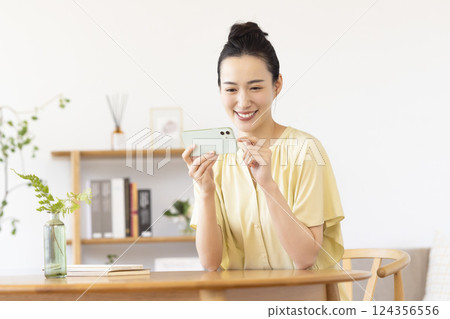woman looking at smartphone in living room woman looking at smartphone in living room 124356556