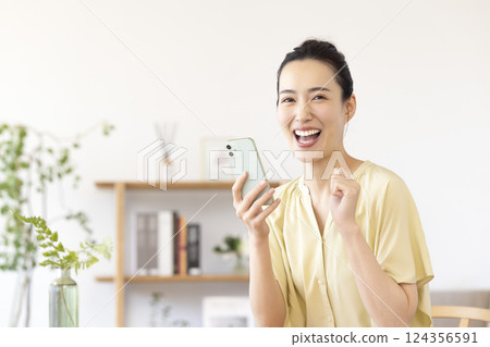 woman looking at smartphone in living room woman looking at smartphone in living room 124356591