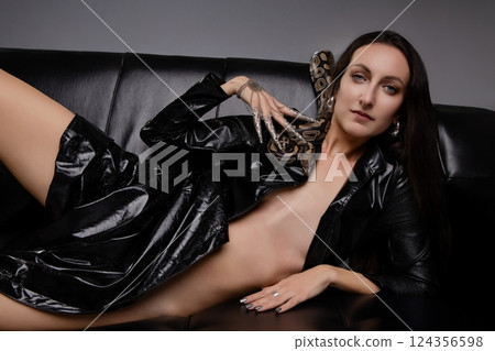Woman poses seductively on black couch with snake while wearing lingerie Woman poses seductively on black couch with snake while wearing lingerie 124356598