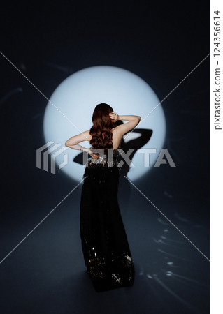 Glamorous Woman in a Metallic Dress Posing Under Dramatic Spotlight Glamorous Woman in a Metallic Dress Posing Under Dramatic Spotlight 124356614