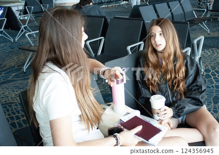 Two girls chatting at the airport before the departure of their fligh 124356945