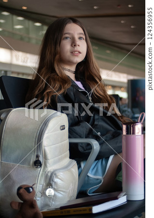 Young girl waits at the airport for her plane's departure announcement 124356955