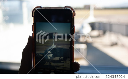 Passenger taking a picture of the plane about to leave with his mobile phone Passenger taking a picture of the plane about to leave with his mobile phone 124357024
