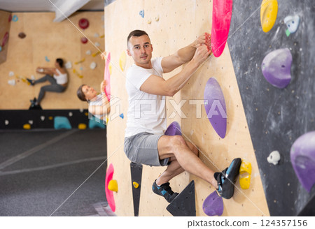 Young man practicing rock climbing on climbing wall 124357156