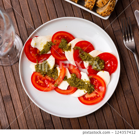 Traditional appetizer of Italian cuisine is Caprese with pesto sauce Traditional appetizer of Italian cuisine is Caprese with pesto sauce 124357412