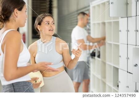 Smiling girl talking with female friend by lockers in bouldering gym 124357490