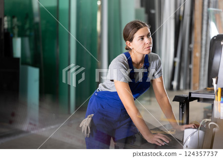 Woman working on CNC glass processing machine at factory Woman working on CNC glass processing machine at factory 124357737