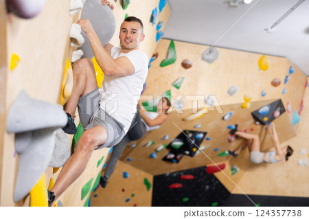 Young man practicing rock climbing on climbing wall Young man practicing rock climbing on climbing wall 124357738