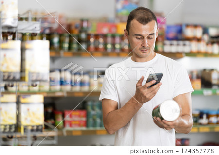 Man in supermarket scan QR code on jar canned food 124357778