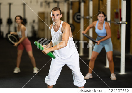 Closeup of athletic sports man standing with plate of barbell in hands in fitness studio 124357780