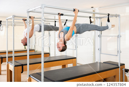 Girl and man do pilates suspended on special sports equipment 124357804