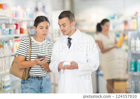 Young woman showing medicine on phone to pharmacist Young woman showing medicine on phone to pharmacist 124357810