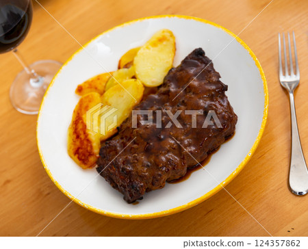 Pork ribs baked under sauce, served with potatoes Pork ribs baked under sauce, served with potatoes 124357862