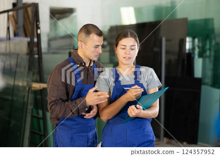 Two glass workshop workers discussing documents 124357952