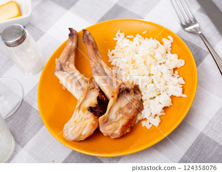 Lunch is served on plate - baked pieces of young rabbit with side dish boiled rice. Lunch is served on plate - baked pieces of young rabbit with side dish boiled rice. 124358076
