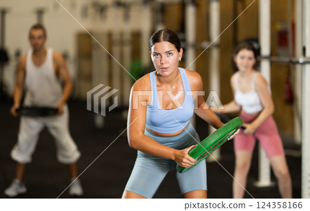 Young woman training with weight plate Young woman training with weight plate 124358166