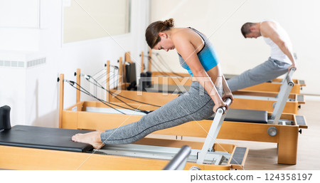 Athletic woman working out with straps in pilates studio 124358197
