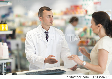 Male pharmacist consulting woman client about medicine indicated in her recipe Male pharmacist consulting woman client about medicine indicated in her recipe 124358213